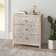 an ornate wooden cabinet next to a potted cactus