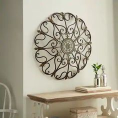 a metal wall hanging on the wall next to a wooden table and white chairs in a room