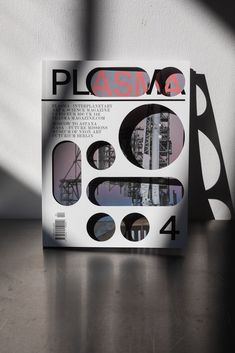 the cover of plasma magazine sitting on a table next to a shadow cast wall and window