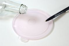 a glass jar with a pencil sticking out of it next to a plastic lid on a table