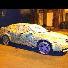 a car made out of plastic bottles sitting on the side of a road at night