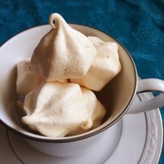 three pieces of meringue in a white cup on a saucer and plate