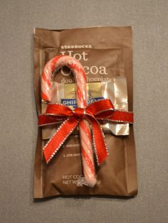 a candy cane wrapped in brown paper and tied with red ribbon on top of a bag