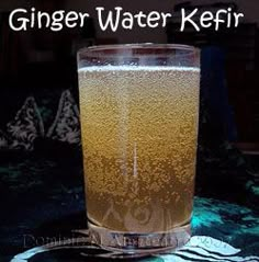 a tall glass filled with liquid sitting on top of a table next to the words ginger water kefir