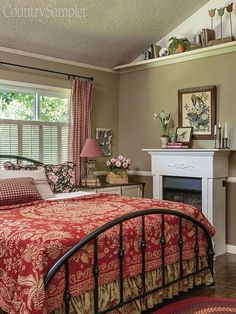 a bed room with a neatly made bed next to a window and a fireplace in the corner