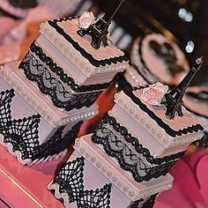 two tiered cake with lace and pearls on top sitting on a pink tablecloth