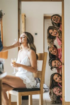 a group of women sitting on top of a wooden chair in front of a mirror