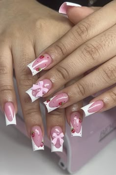 a woman's hands with pink and white nail designs on their nails, holding a box