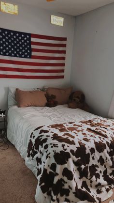 a bed with a cow print comforter and american flag on the wall above it