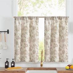 a kitchen with a sink, counter top and window covered in curtained drapes