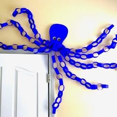 an octopus made out of blue plastic chains hangs on the wall next to a door