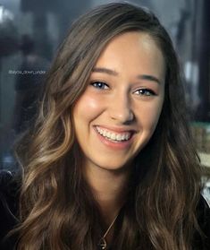 a woman with long hair smiling at the camera