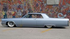 an old car parked in front of a graffiti covered wall