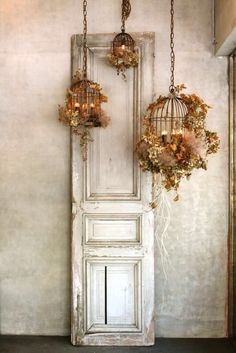 an old door with two birdcages hanging from it's sides and some flowers in the middle