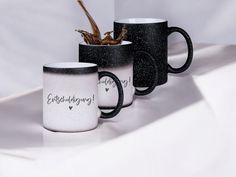 three black and white coffee mugs with writing on them