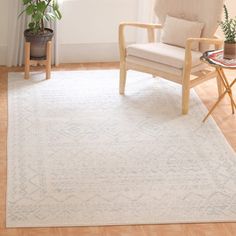 a living room area with a chair, potted plant and rug on the floor