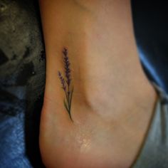 a small flower tattoo on the side of a woman's foot with purple flowers