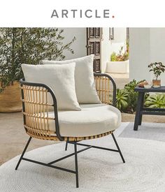 a wicker chair sitting on top of a white rug next to a black table