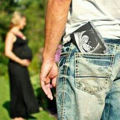 a pregnant woman standing next to a man holding the belly of his baby in her pocket