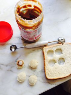 an open jar of peanut butter and jelly on a marble counter top with spoons