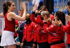 the women's tennis team is applauded by their coach, who is wearing a face mask