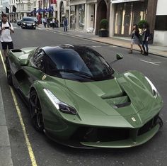 the green sports car is parked on the side of the street