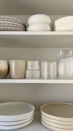 white dishes and plates are on shelves in a room with neutral colors, like glassware