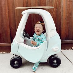 a baby sitting in a toy car on the ground