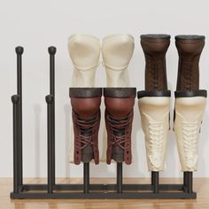 four different types of boots are lined up in a row on a wooden table with black poles