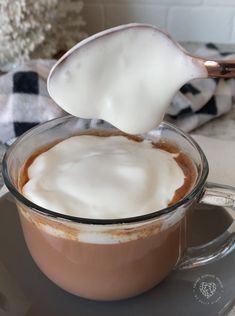 a spoon is lifting some kind of liquid out of a cup filled with hot chocolate