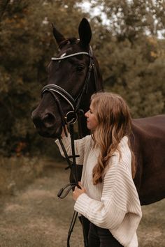 a woman standing next to a brown horse