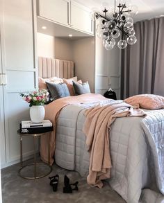 a bedroom with a chandelier hanging from the ceiling next to a bed covered in blankets and pillows