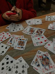 playing cards are scattered on the table, with one person holding a red cell phone