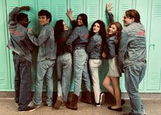 a group of young people standing next to each other in front of lockers with their hands up