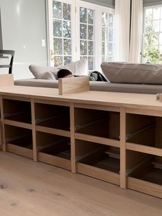 a living room filled with furniture and lots of shelves next to a couch on top of a hard wood floor