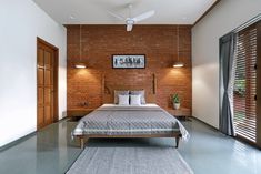 a bedroom with brick walls and flooring is shown in this image, there is a bed that has two pillows on it