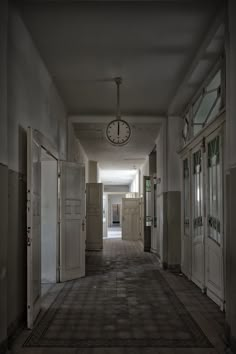 an empty hallway with several doors and a clock on the wall in front of it