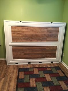 a room with green walls and wood flooring on the wall, there is a rug that has been placed in front of it