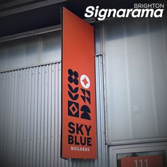 an orange sign hanging from the side of a building next to a metal wall and door