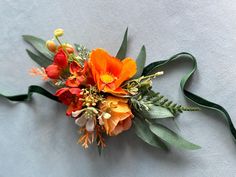 an orange and red flower arrangement with green leaves