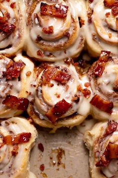 a pan filled with cinnamon rolls covered in icing and bacon on top of it