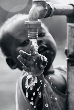 a little boy drinking water from a faucet that is running out of it