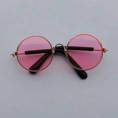 a pair of pink tinted glasses sitting on top of a gray surface with black handles