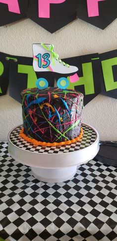 a birthday cake sitting on top of a black and white checkerboard tablecloth