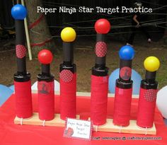 a bunch of red and yellow poles with some balls on them in front of a sign that says paper ninja target practice