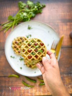 a person holding a waffle on top of a white plate next to a fork