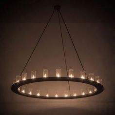 a circular chandelier with many lit candles hanging from the ceiling in a dark room