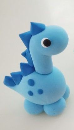 two blue toy dinosaurs sitting next to each other on a white surface with one looking at the camera