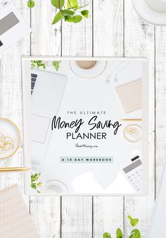 the ultimate money saving planner is displayed on a white table with green plants and other items