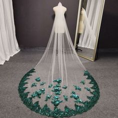 a wedding veil with green sequins on the bottom is displayed in front of a mirror